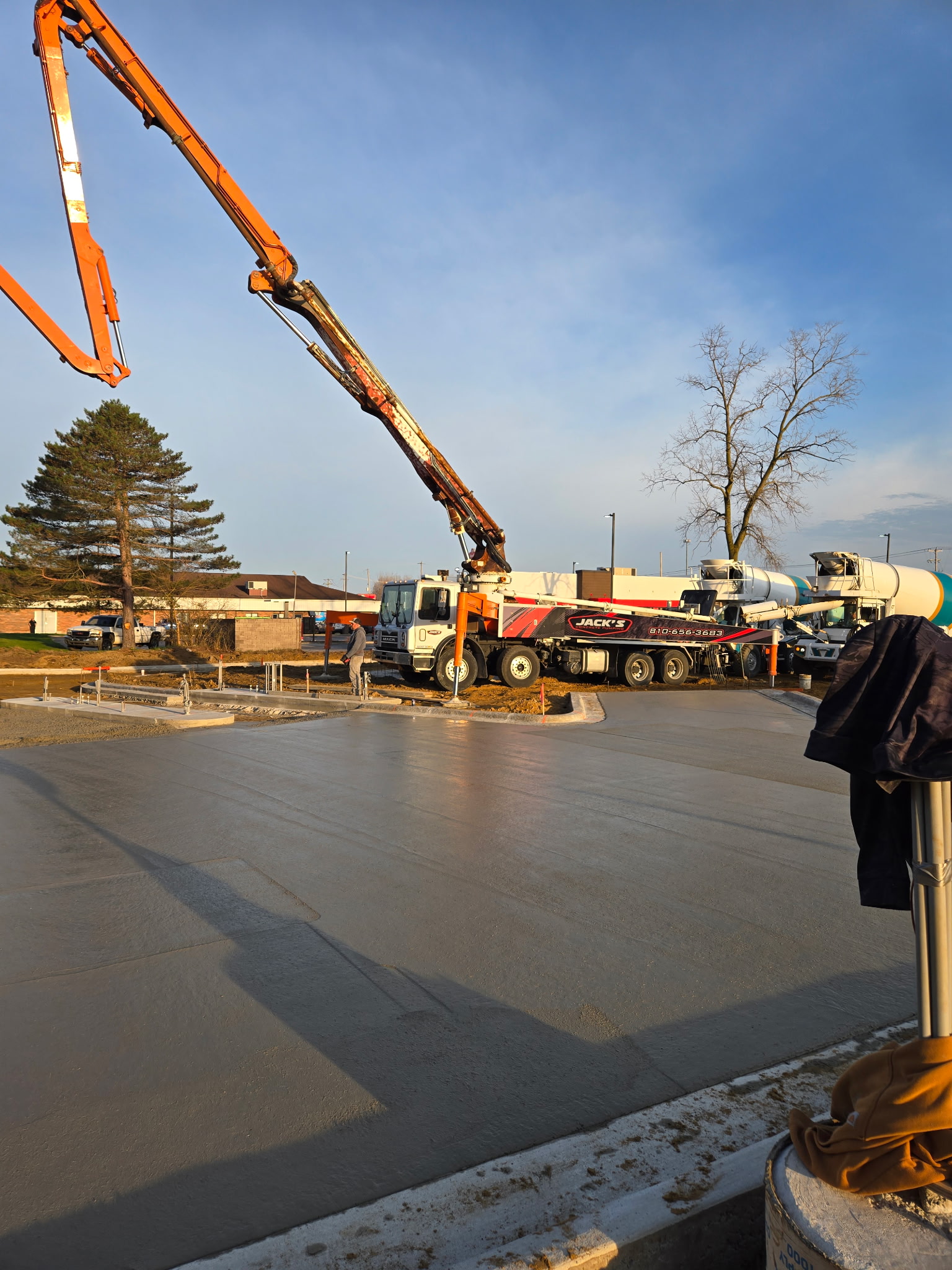 Construction crew finishing a concrete pour at sunset